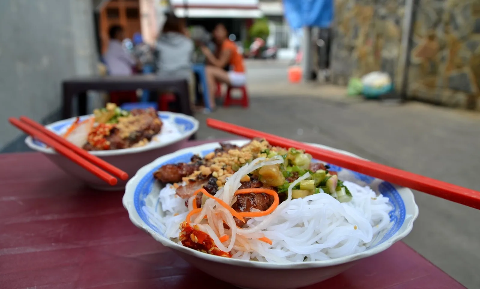 Bowls of bun thit nuong with grilled pork and rice vermicelli served on a street-side table in Ho Chi Minh City.