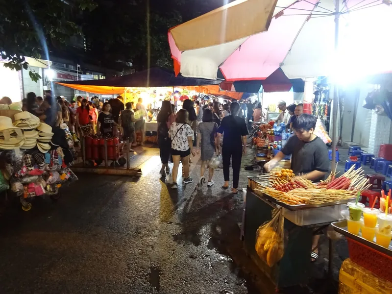 Shoppers browse street food stalls grilling skewers at a bustling night market in Hanoi's Old Quarter.