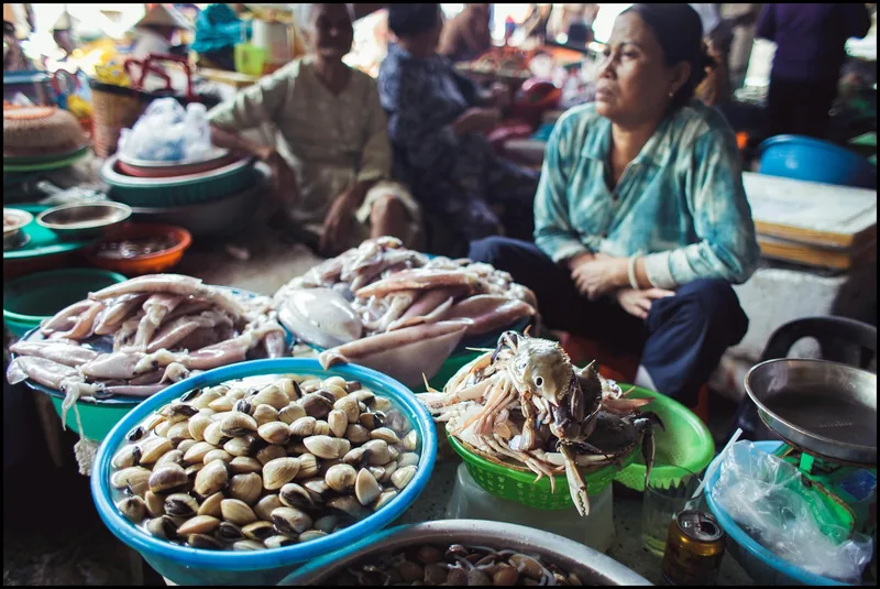 A vendor sits behind basins of fresh clams, squid and crabs at Hoi An central market.