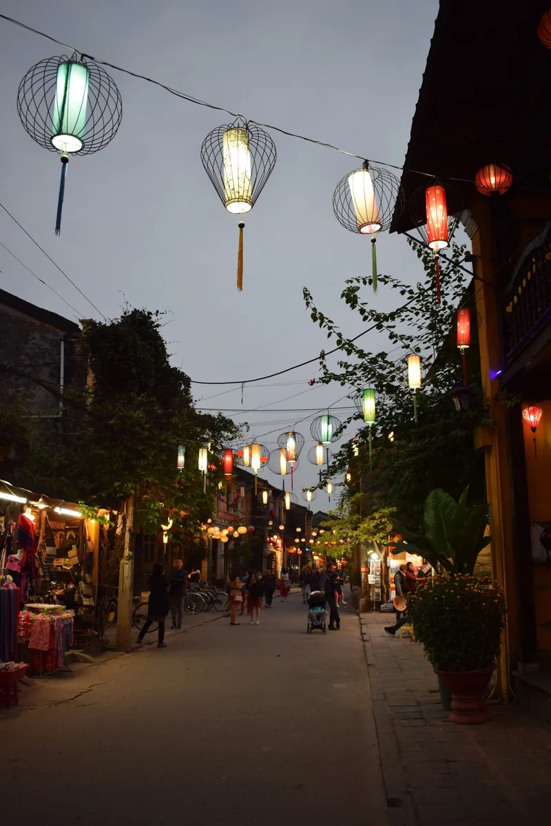 Colorful silk lanterns hang over a quiet evening street in Hoi An's old town.