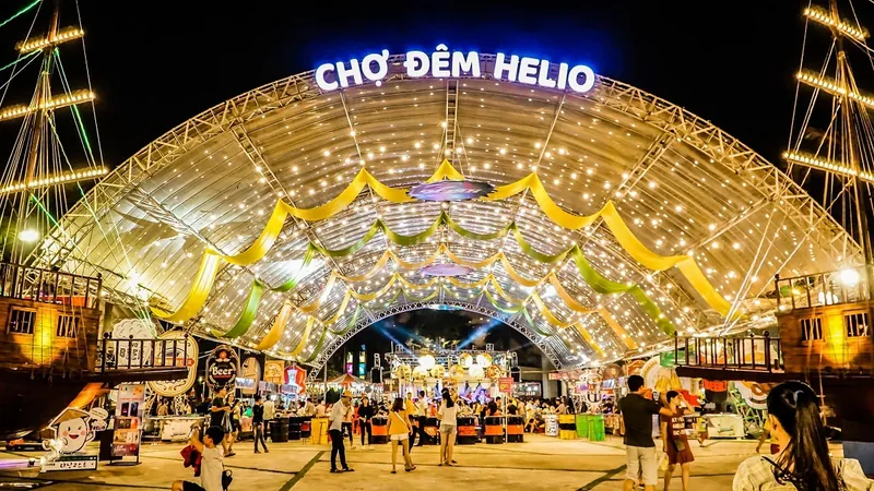 Illuminated arched roof and colorful stalls at Cho Dem Helio night market in Da Nang after dark.